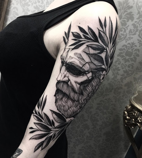 Artística manga da tatuagem. A tatuagem mostra um homem, que é, presumivelmente, um estudioso com uma coroa de folhas na cabeça. Ele parece estar fechando os olhos, como ele se ajoelhar na frente dele. (Foto: Fontes de imagem)
