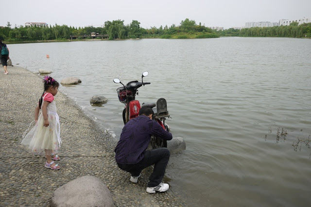 another man washing his motorbike while a young girl watches