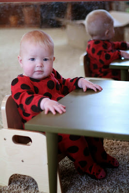 a very small table and chair with a tot sitting down to eat