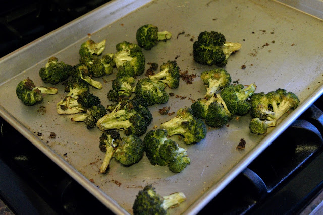 The broccoli florets, on the baking sheet, after they have roasted. 