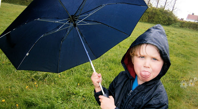 young boy in rain with umbrella 
