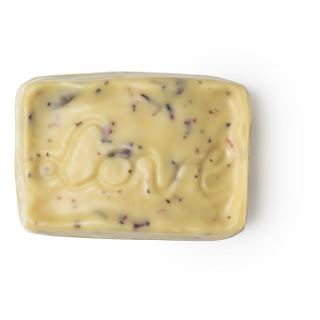 A rectangular white massage bar filled with bits of yellow rose petals on a white background