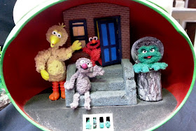 Miniature Sesame Street stoop with Big Bird, Elmo, Grover and Oscar on it.