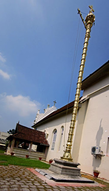tall gold lamp tower at the entrance to the Kerala ancient church of Cheriya Pally