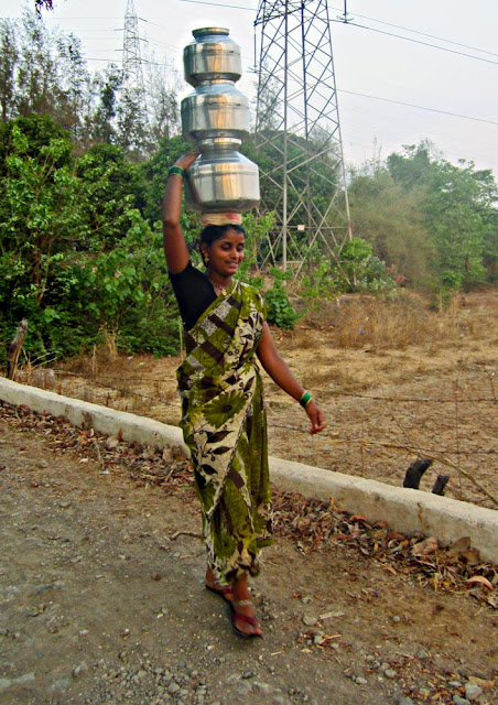 woman carrying steel pots on head