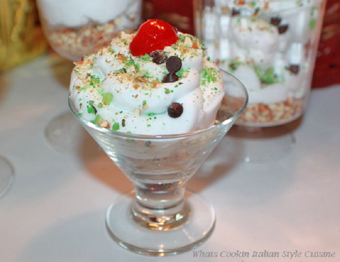 this is how to make a delicious cannoli filling into a mousse dessert. The mousse is layered with crushed cannoli shells topped with cannoli mousse and garnished with mini chocolate chips, crushed pistachios and a cherry on top for a festive christmas no bake dessert.