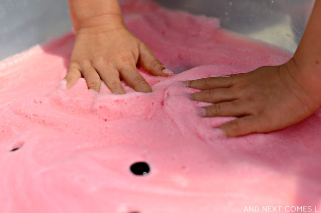 Kids' hands in pink soap foam sensory bin