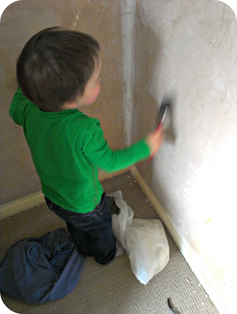 Small boy painting the plaster with water