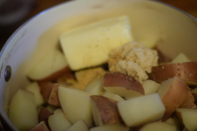 Butter, horseradish, and seasonings being added to the cooked red potatoes. 