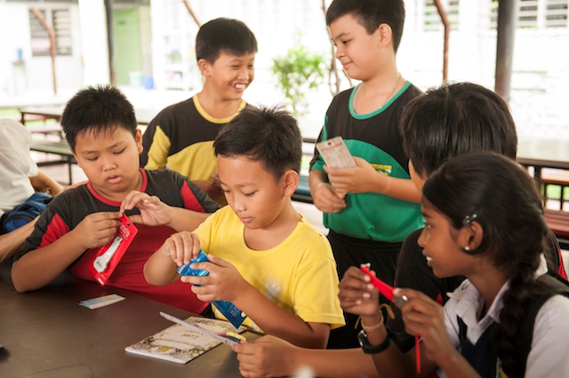 Kids at SK La Salle Jinjang excitedly unwrapping their gifts with their friends