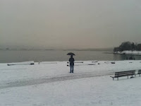 A lonely person with black umbrella at the snow-covered beach