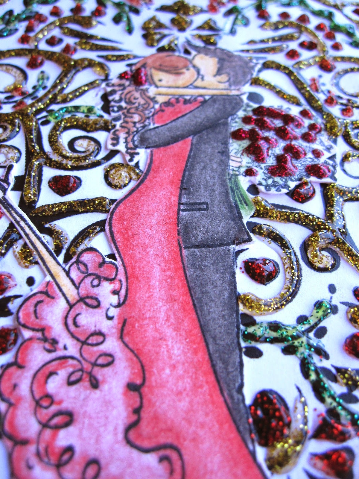 detalle de tarjeta de scrapbooking para San Valentín con corazón de filigrana decorado con glitter glue rojo, verde y amarillo y pareja de novios coloreada besándose