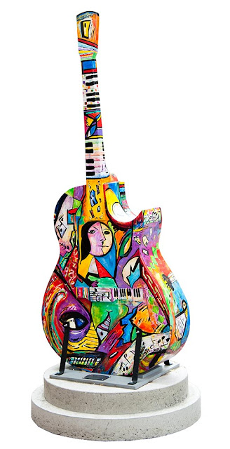 large wooden painted guitar on display in downtown Orillia, the design on this one is multicolour abstract in a picaso-like style