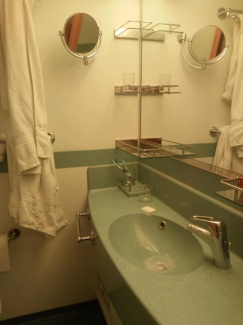 La salle de bain classique des navires Costa : douche à l'italienne, toilettes, lavabo avec miroir.