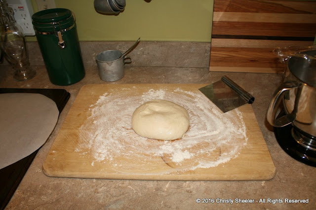 One half of the prepared dough is sitting on a lightly floured surface.