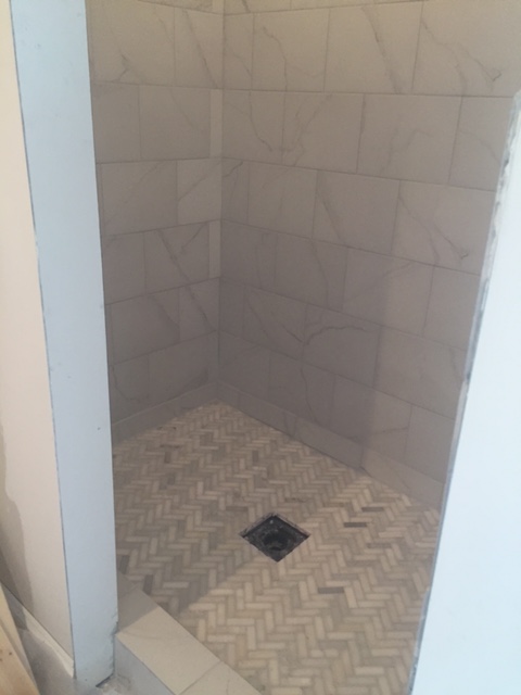 Herringbone marble mosaic shower floor under construction - Hello Lovely Studio