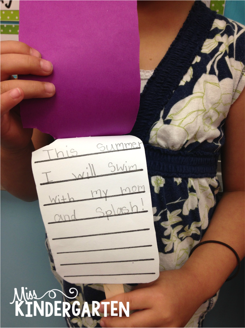 A student holds a purple popsicle craft and writing activity
