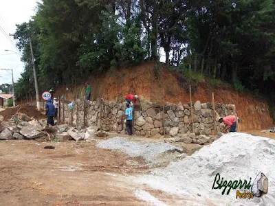 Execução do muro de pedra rústica sendo o tipo de pedra moledo na face do muro e no enchimento a pedra rachão. Muro de pedra com junta seca sem cimento nas juntas.