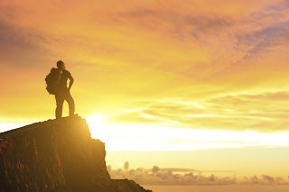 man on top of mountain watching sunset