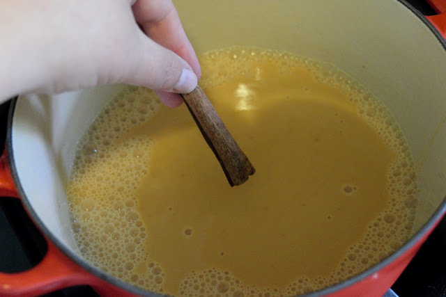 A cinnamon stick being added to the pot. 