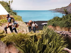 Diorama of 19th-century soldiers moving supplies from the beach up to an encampment.