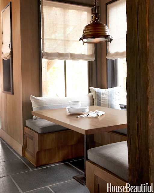 Banquette in beautiful kitchen. "Pillows covered in french ticking and bench cushions in Perennials' Ishi make a cozy breakfast nook. 'The industrial light fixture adds structure and weight to the space,' Wick says."