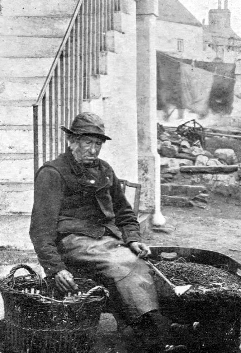 A black-and-white image of a 19th century Scottish fisherman mending his nets