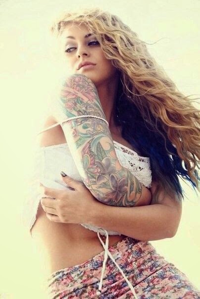 Preciosa mujer de pelo rubio largo con el brazo tatuado de flores