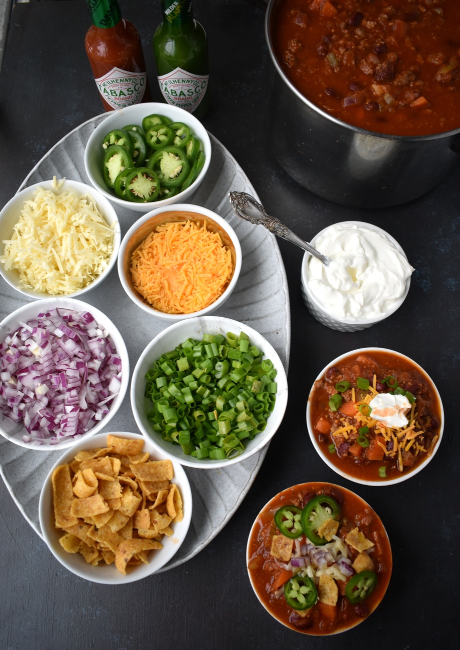 The Ultimate Chili Bar features a spicy turkey chili and all the toppings including shredded cheese, red onions, jalapenos, hot sauce, corn chips, sour cream and green onions. Perfect for entertaining and easy to make in large quantities.