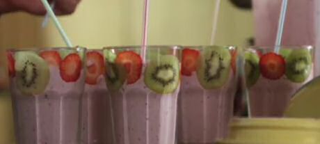 Basis recept om smoothies te maken met bevroren kleinfruit, roomijs, yoghurt en melk, glazen versierd met dunne schijfjes fruit