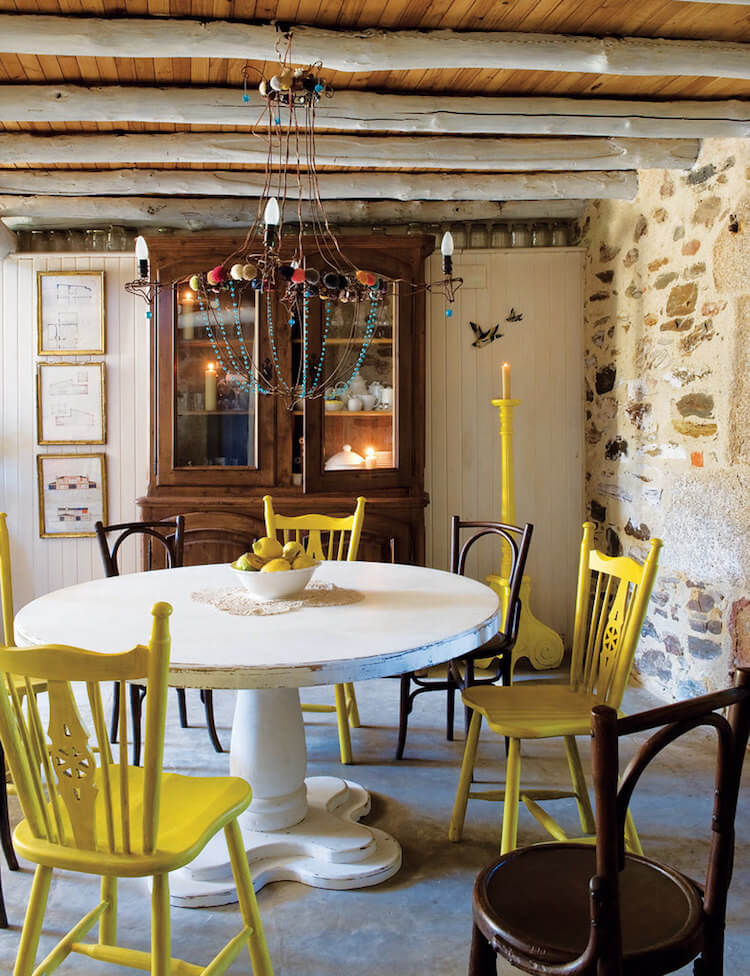 detalle del comedor de una casa rústica con sillas de colores y de fondo una vitrina antigua