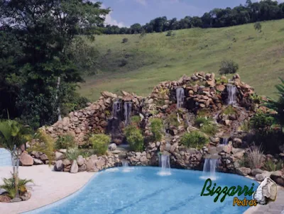 Execução da cascata de pedra na piscina com pedras ornamentais com o lago com a cachoeira de pedra encostada na piscina e a execução do paisagismo.