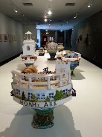 Selection of miniature wooden painted artist's arks on display in a gallery.
