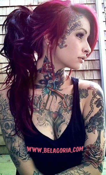 pelirroja apoyada en una pared, lleva tatuajes por todo el cuerpo, son tatuajes tradicionales