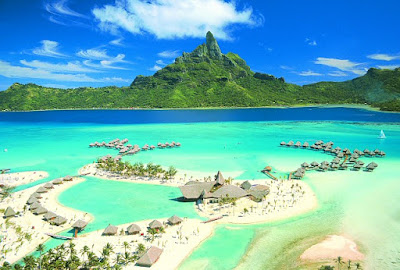 Vue aérienne d'un Atoll à  Tahiti, avec des bungalows sur pilotis.