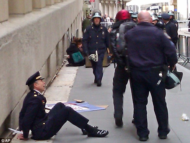 Sitting against a wall in full dress uniform with his hands cuffed ...