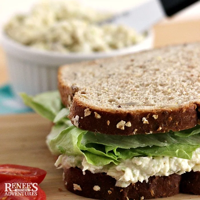 Southern Style Chicken salad recipe in white bowl in background with a chicken salad recipe sandwich on whole grain with lettuce in the foreground
