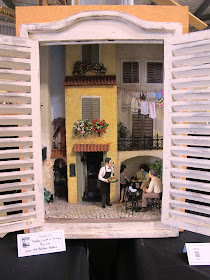Cupboard with a one-twelfth scale miniature scene of a European courtyard with a waiter serving diners inside it
