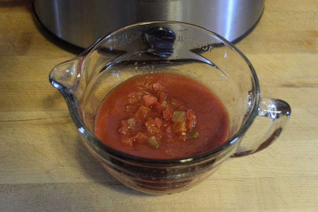 The diced tomatoes with green chillies and the tomato sauce being combined together in a bowl.