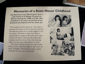 Placard explaining the story behind the miniature 1940s child's bedroom scene 'Memories of a State House Childhood'