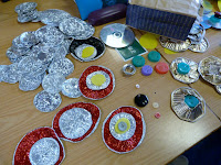 Peacock's tail eyes made from concentric circles of red and silver foil, plastic, milk bottle tops, buttons and beads