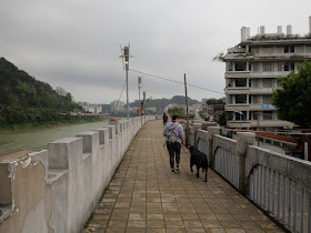 woman walking a dog on a wall bordering the Gui River (桂江) in Wuzhou (梧州)