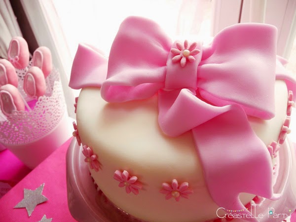 gâteau au chocolat décoré de pâte à sucre blanche et d'un gros nœud rose