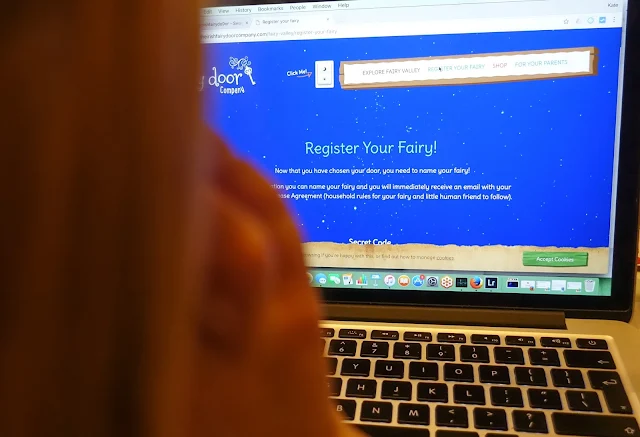 A shadow of a young girl in front of a MacBook showing a website to register the fairy