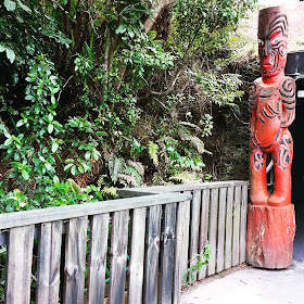 Maori carving at the edge of a path through the bush.