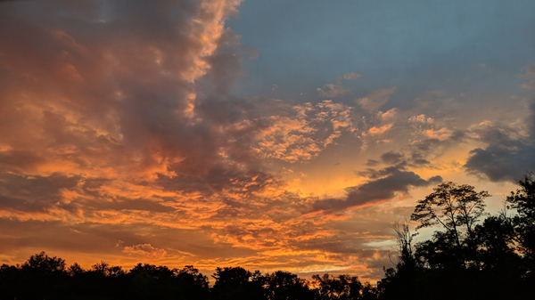 image of an orange and grey-blue sky filled with clouds at sunset