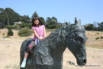 child astride statue in Blackie's Pasture in Tiburon, California