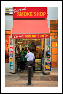 a photograph of a man smoking in front of a tobacco shop in new york