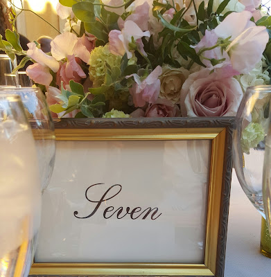 Número de mesa en marco dorado bajo un centro de flores