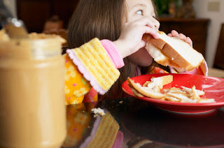 Girl eating a peanut butter sandwich MP900422681